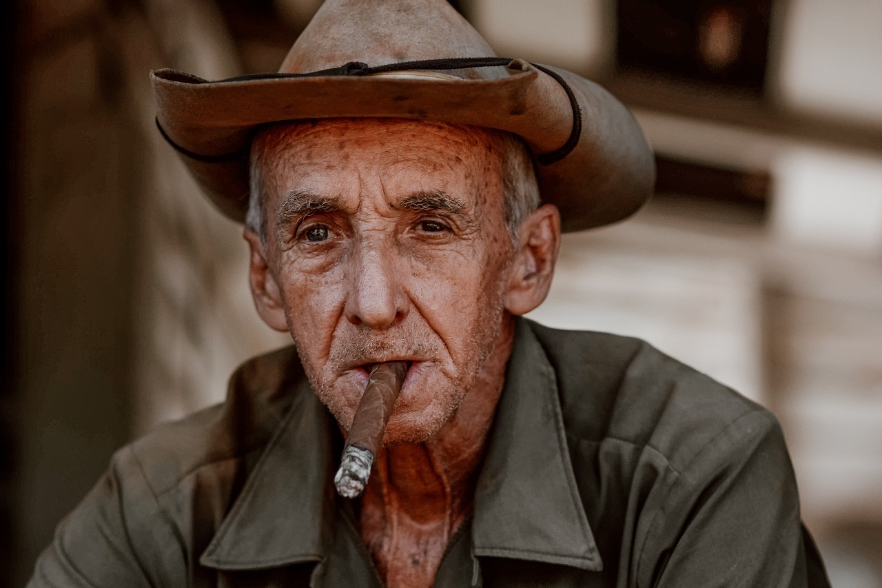 Elderly man in contemplation while slowly savoring the taste of a finely crafted cigar, embodying the true art of cigar smoking.