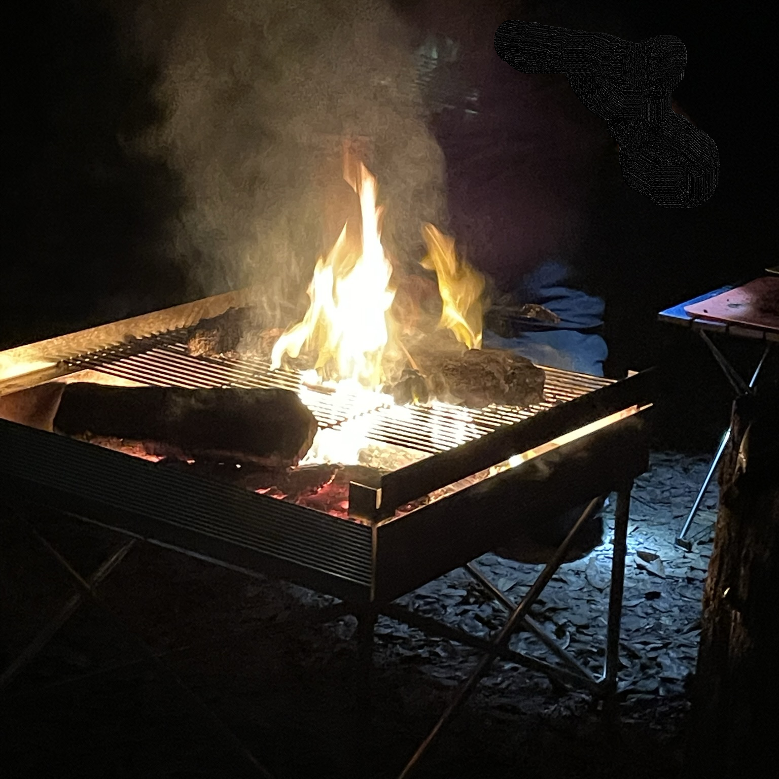 A vibrant camping fire at night ignited using fire starters for camping, showcasing the utility of a camping fire starter