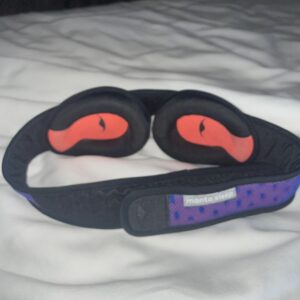 The Manta sleep mask on a bed. Showing the adjustable eye cups of the manta mask