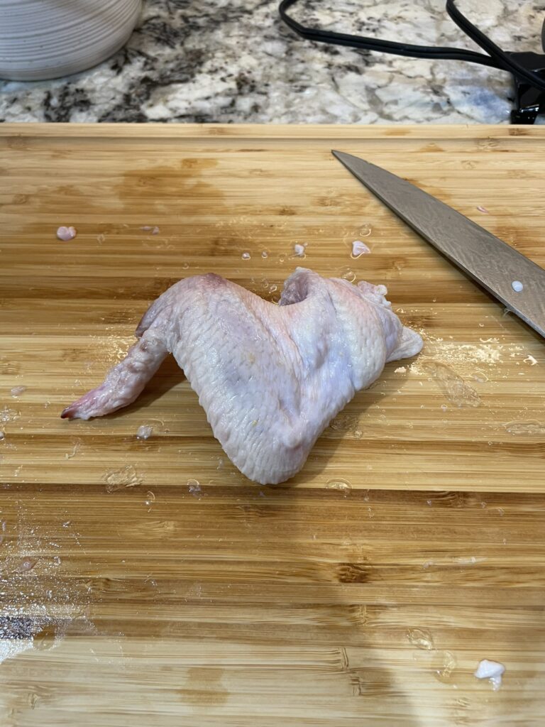 Smoked wings - wing on the cutting board ready for trimming.