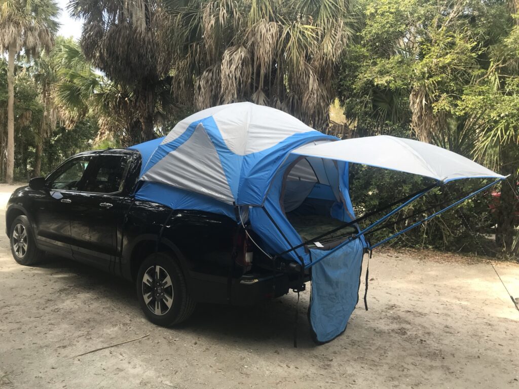 A truck with a tent attachment set up for camping, embodying the spirit of truck camping adventures.