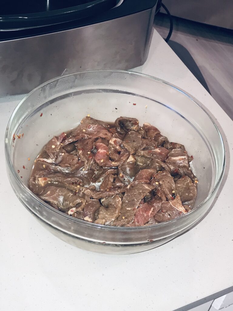 Marinated beef jerky in a bowl, ready to be cooked using Ninja Foodi Grill recipes.