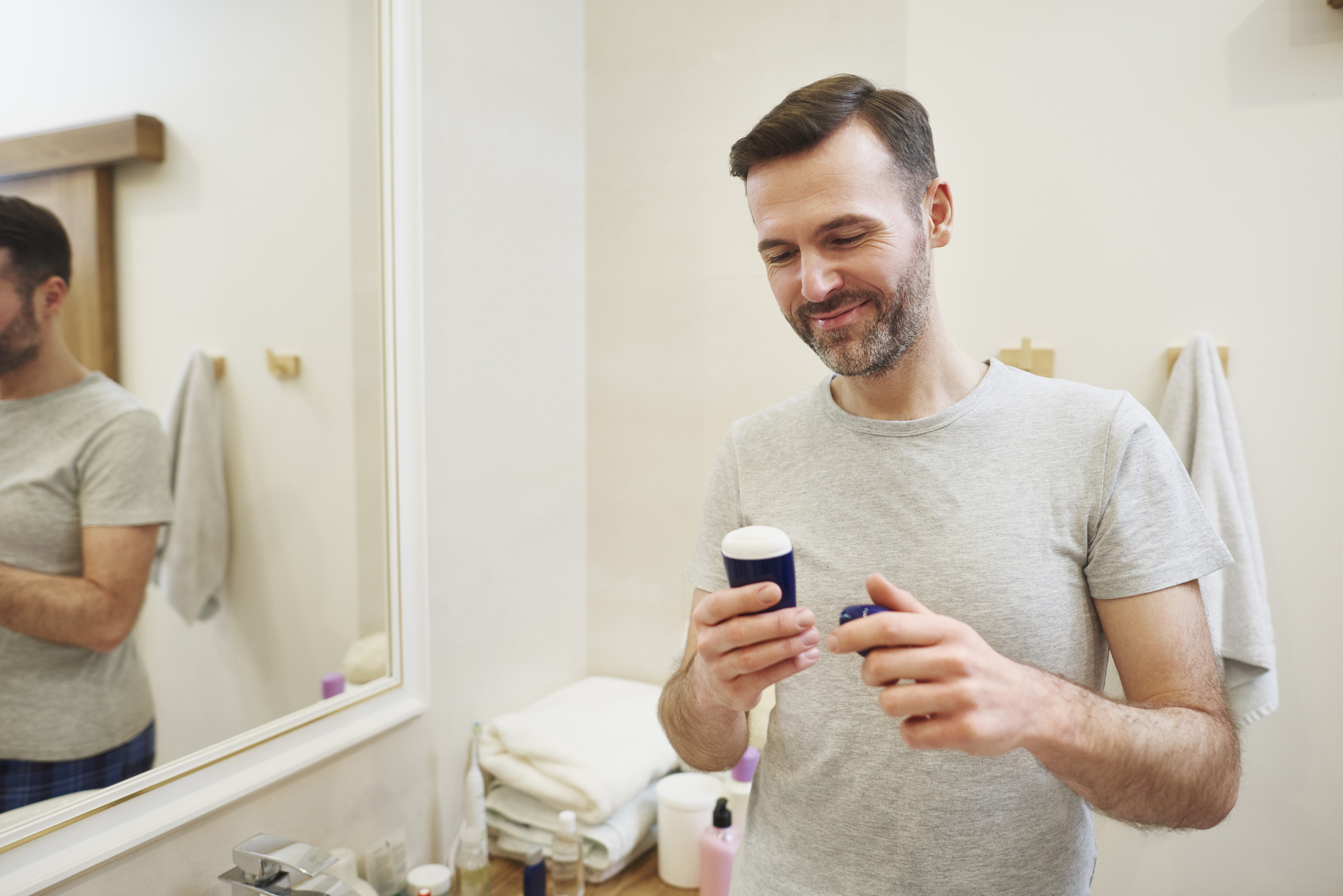 A happy man looking at his aluminum free deodorant for men