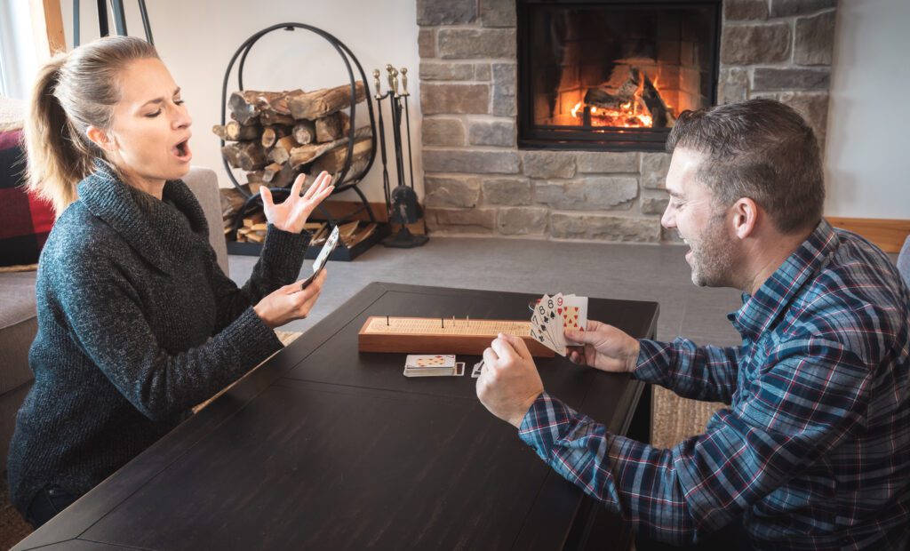 Man and wife engrossed in a game of cribbage, wife experiencing a cribbage skunk, highlighting the importance of understanding the cribbage scoring chart