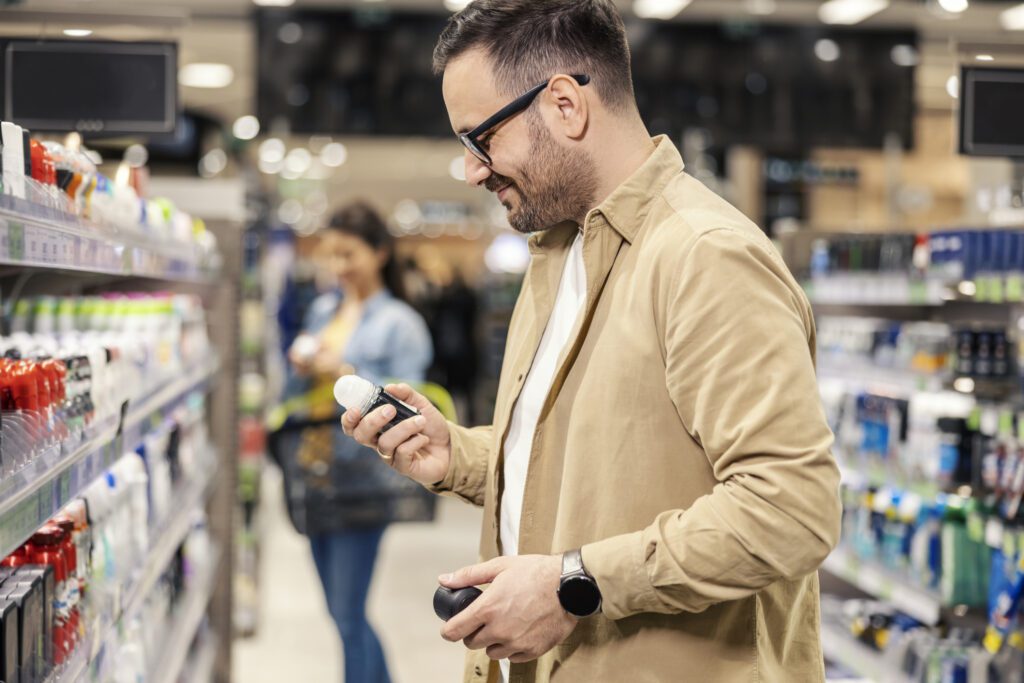 Man looking through different deodorant options at a store, including the AOS deodorant a aluminum free deodorant for men