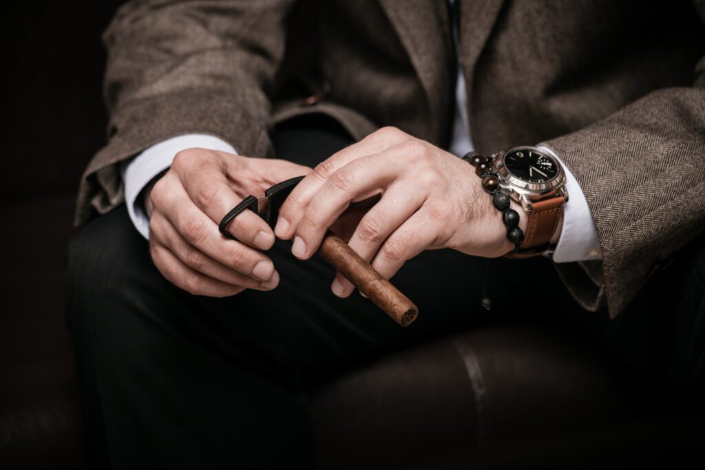 A man is seen demonstrating how to cut a cigar with a professional cigar cutter.