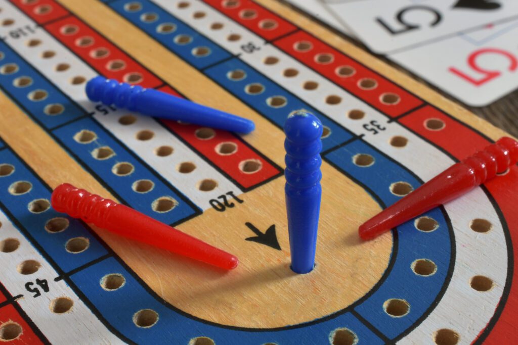 A peg in a crib board reaching 121 to signify a win in a game of cribbage, demonstrating how to play cribbage