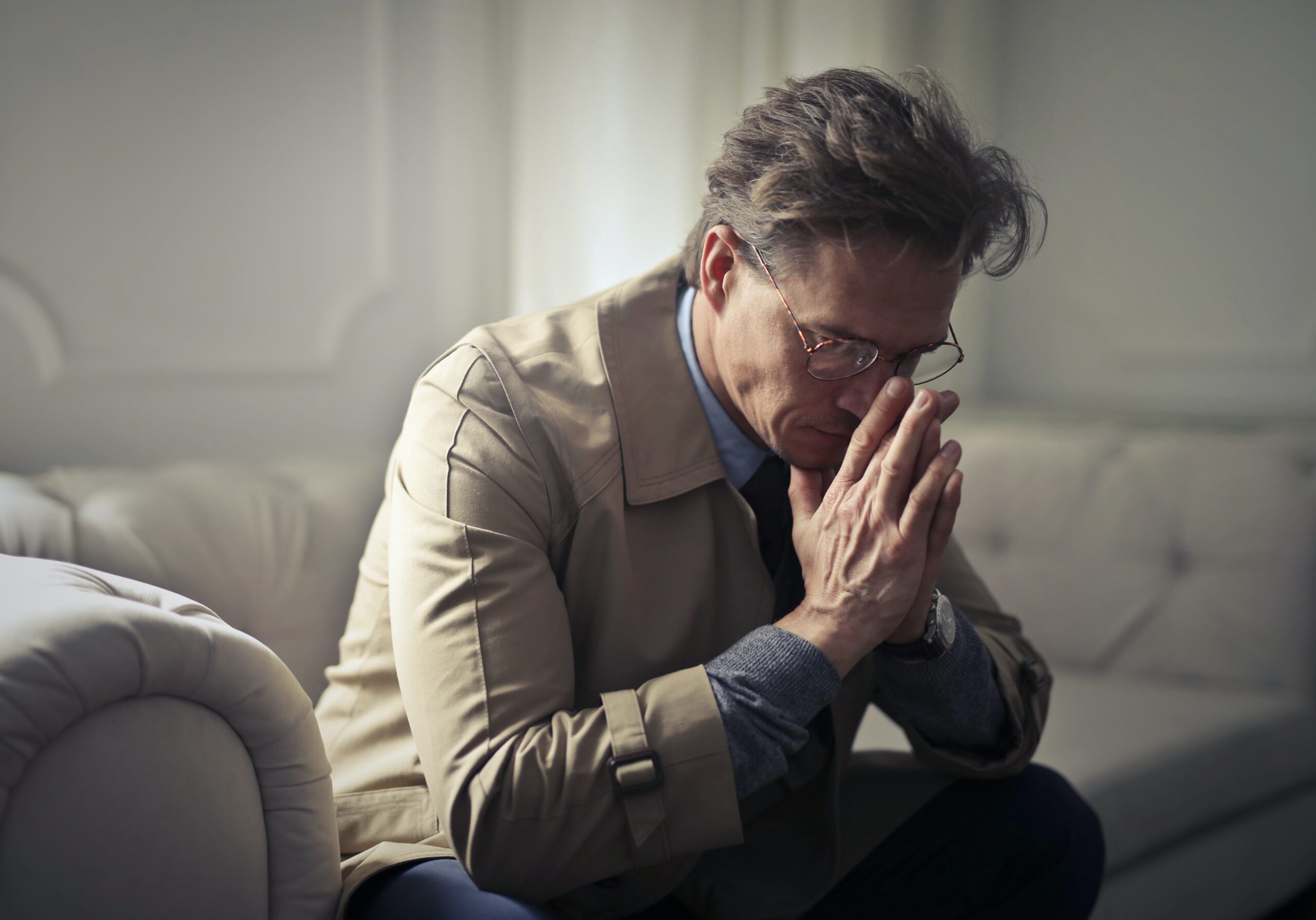 Man sitting stressed out with his hands on his face, struggling with surviving the holidays