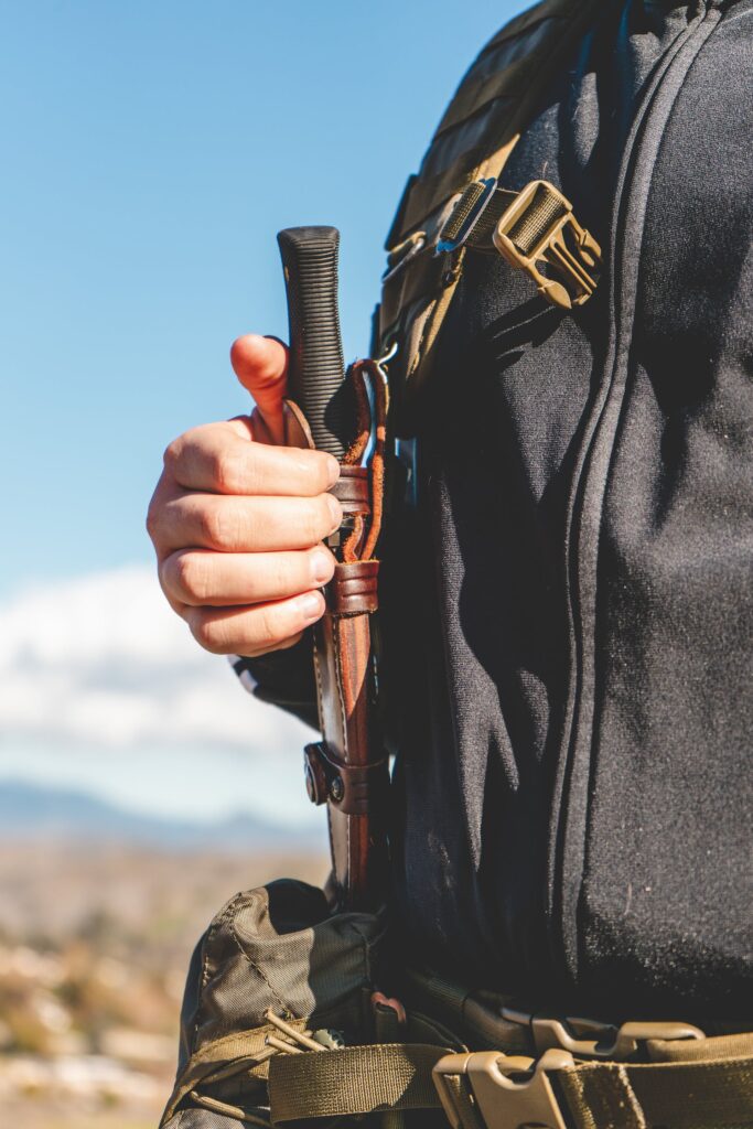 Survival knife sheathed in a belt holster outdoors, illustrating the convenient accessibility of a belt knife.