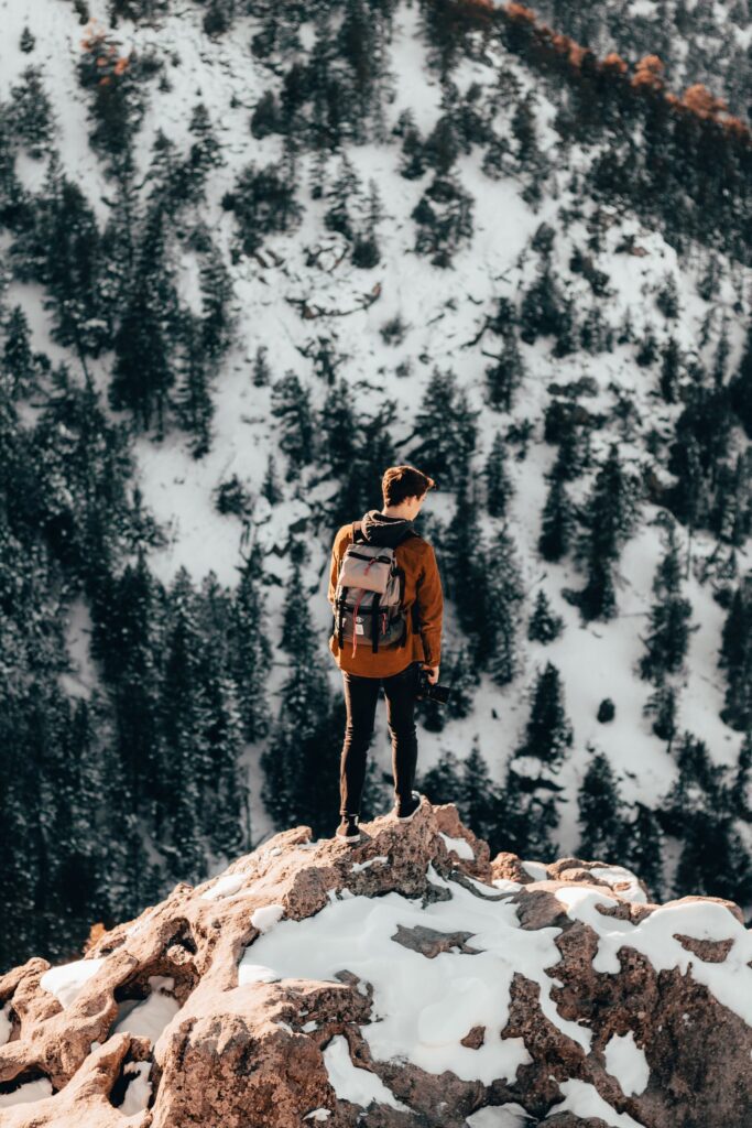 Man on mountain top wearing the ultimate best travel backpack for men, designed for peak performance.