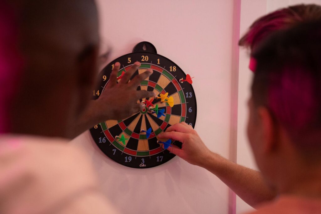 A group of friends learning how to play cricket darts on an electronic dartboard.