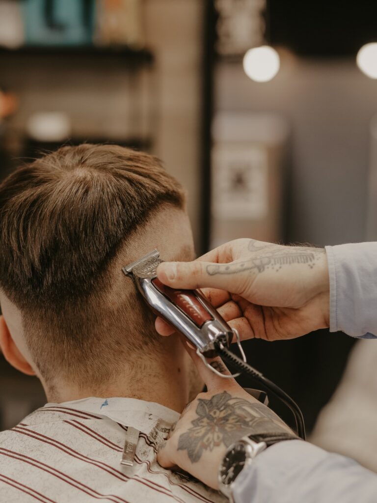 Barber in action, giving a customer a high fade haircut, a more drastic version of the low taper fade.