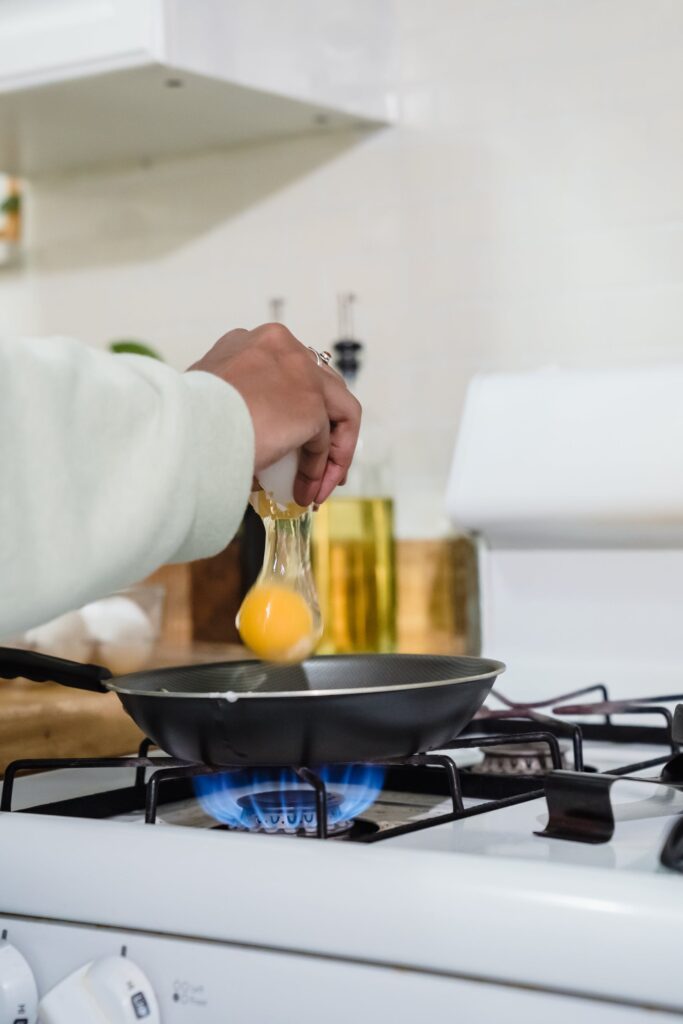 An egg being cracked carefully into a frying pan, showcasing the initial step in preparing an egg over hard.