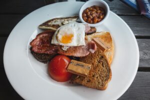 A perfectly cooked over hard egg served on a breakfast plate with toast and bacon, illustrating the final result of the over hard egg technique.