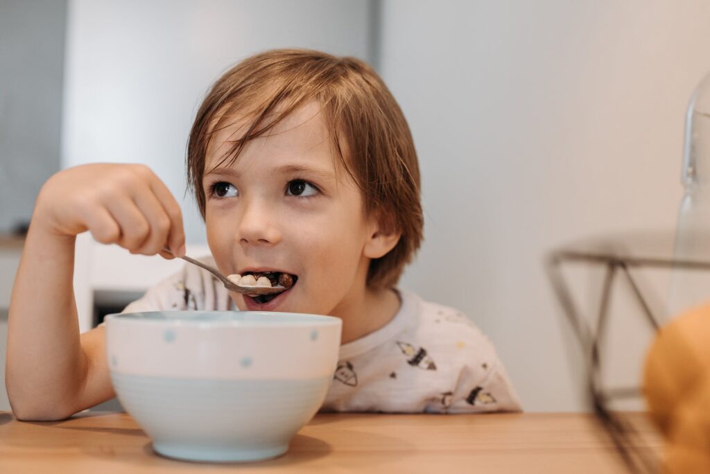 A child enjoying a bowl of sugary cereal, such as Fruity Pebbles.