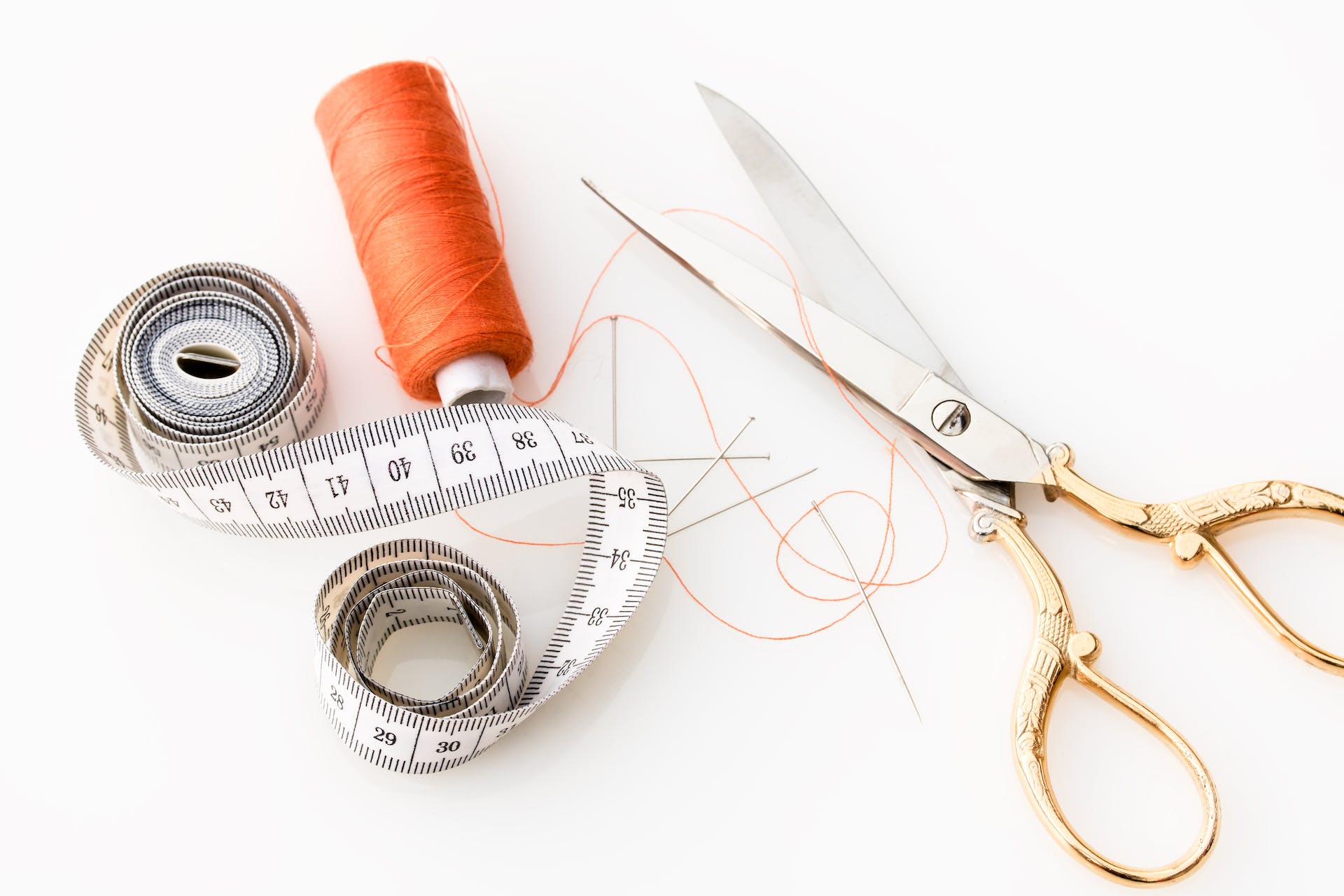 An array of sewing supplies, including needles, thread, scissors, and fabric patches, laid out for a tutorial on how to sew a hole.