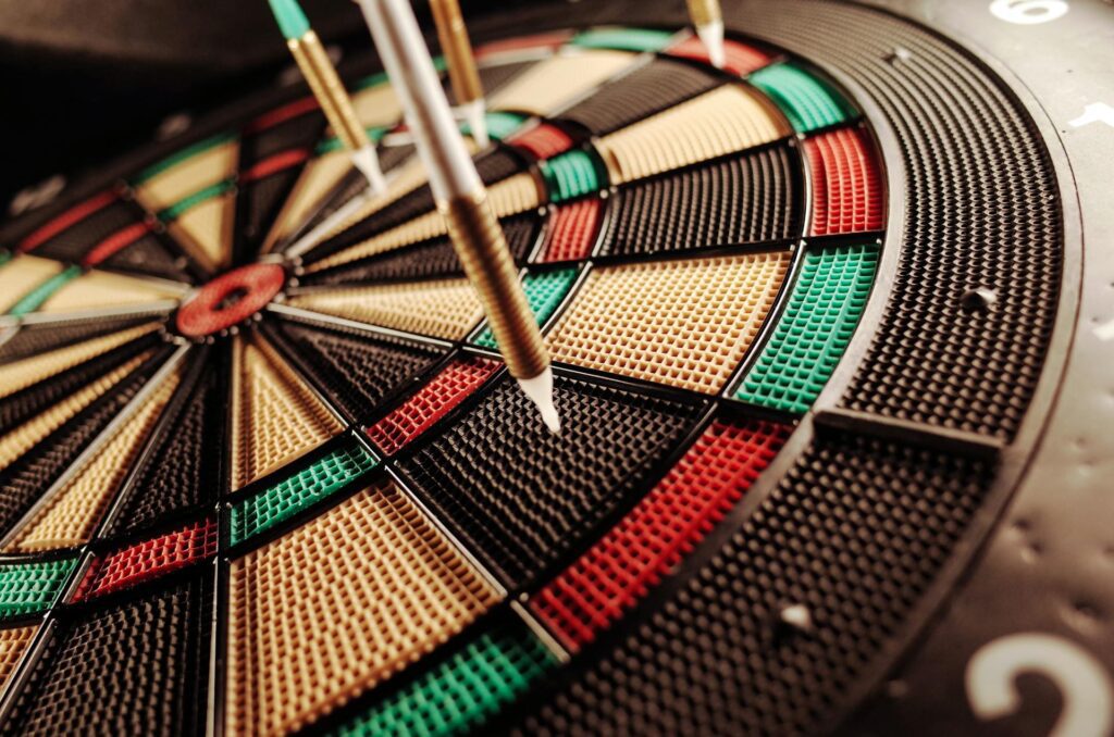 Multiple darts lodged in an electric dart board after a round of gameplay.