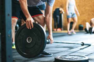 Man adding weight to the barbell for landmine press, an effective workout for core stability and balance.