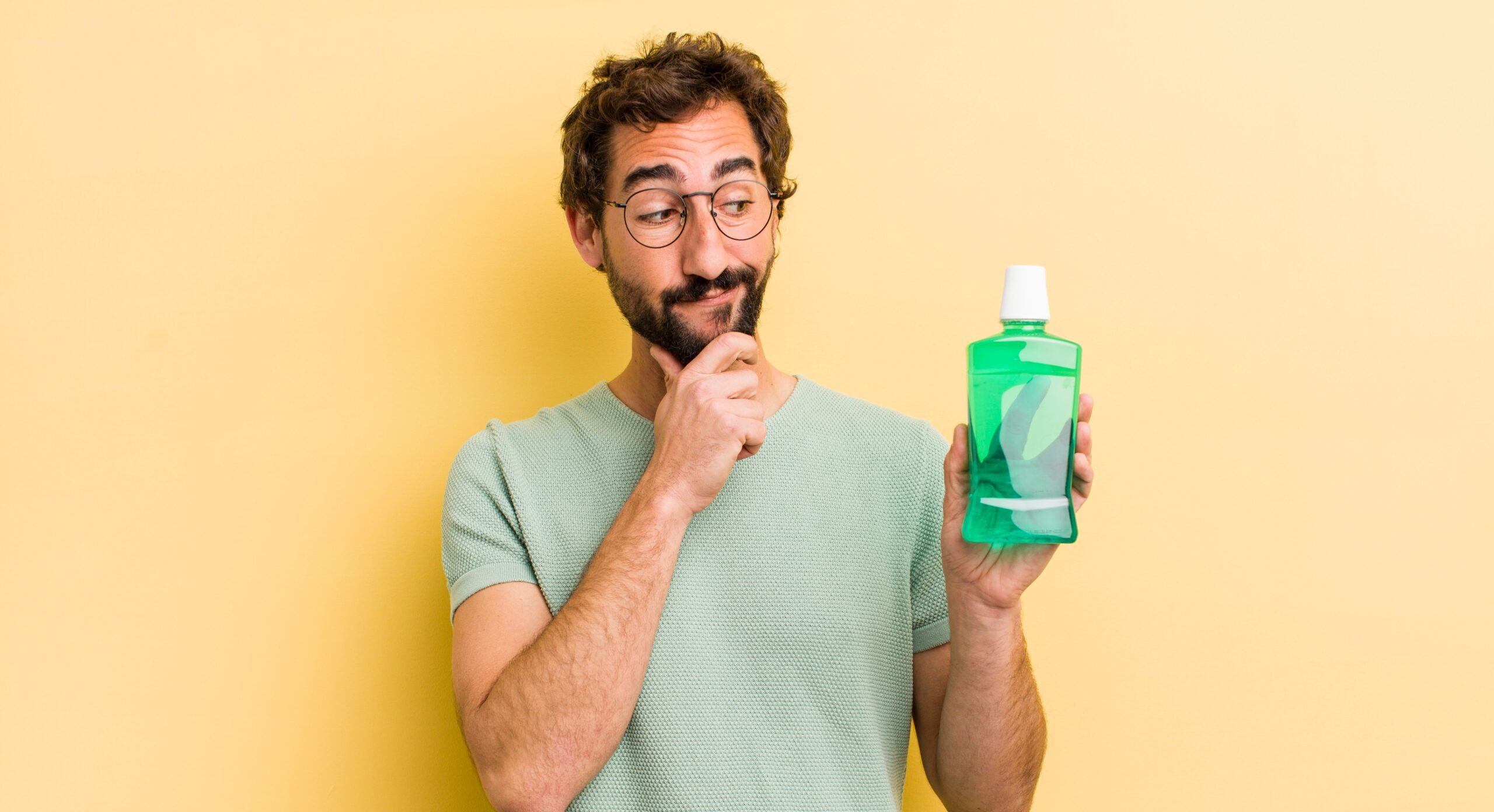 A man holding a bottle of the best mouthwash designed to combat bad breath, showcasing the product name and packaging.